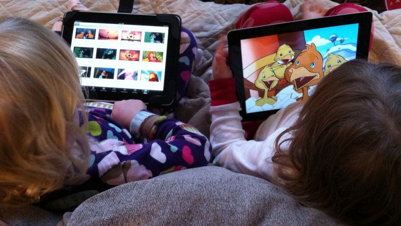 Foto uppifrån och bakifrån på två barn med varsin iPad i knät. Flickr cc-licens: Wayan Vota