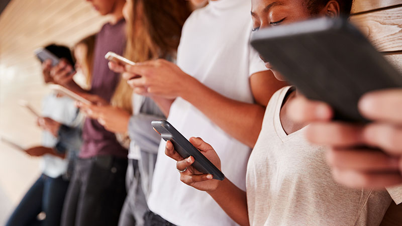 Unga människor med telefoner i händerna. Foto: Shutterstock.